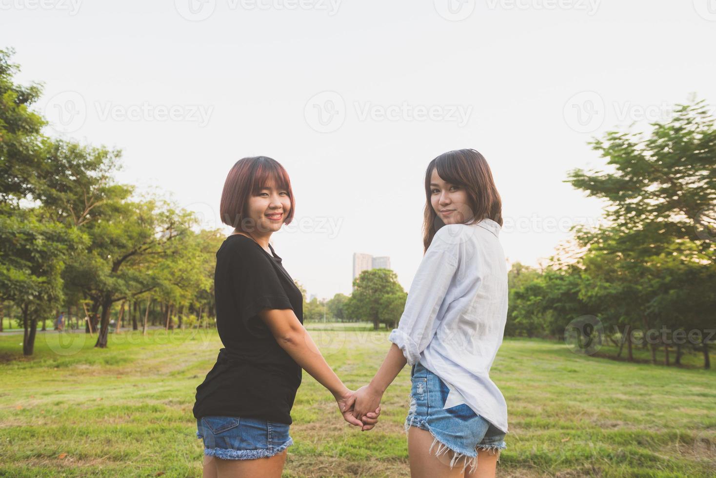 lgbt lesbische vrouwen paar momenten geluk. lesbische vrouwen koppelen samen buitenshuis concept. lesbisch koppel hand in hand samen relatie verliefd. twee aziatische vrouwen die samen plezier hebben in het park. foto