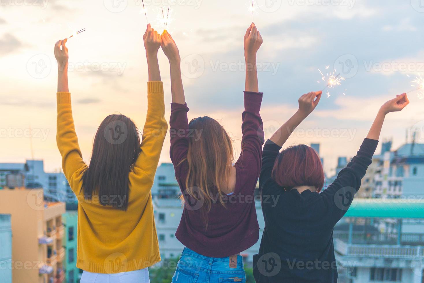 buitenopname van jonge mensen op een feestje op het dak. gelukkige groep aziatische vriendinnen geniet en speelt sterretje op het dakfeest bij avondzonsondergang. vakantie viering feestelijke partij. tiener levensstijl feest. foto