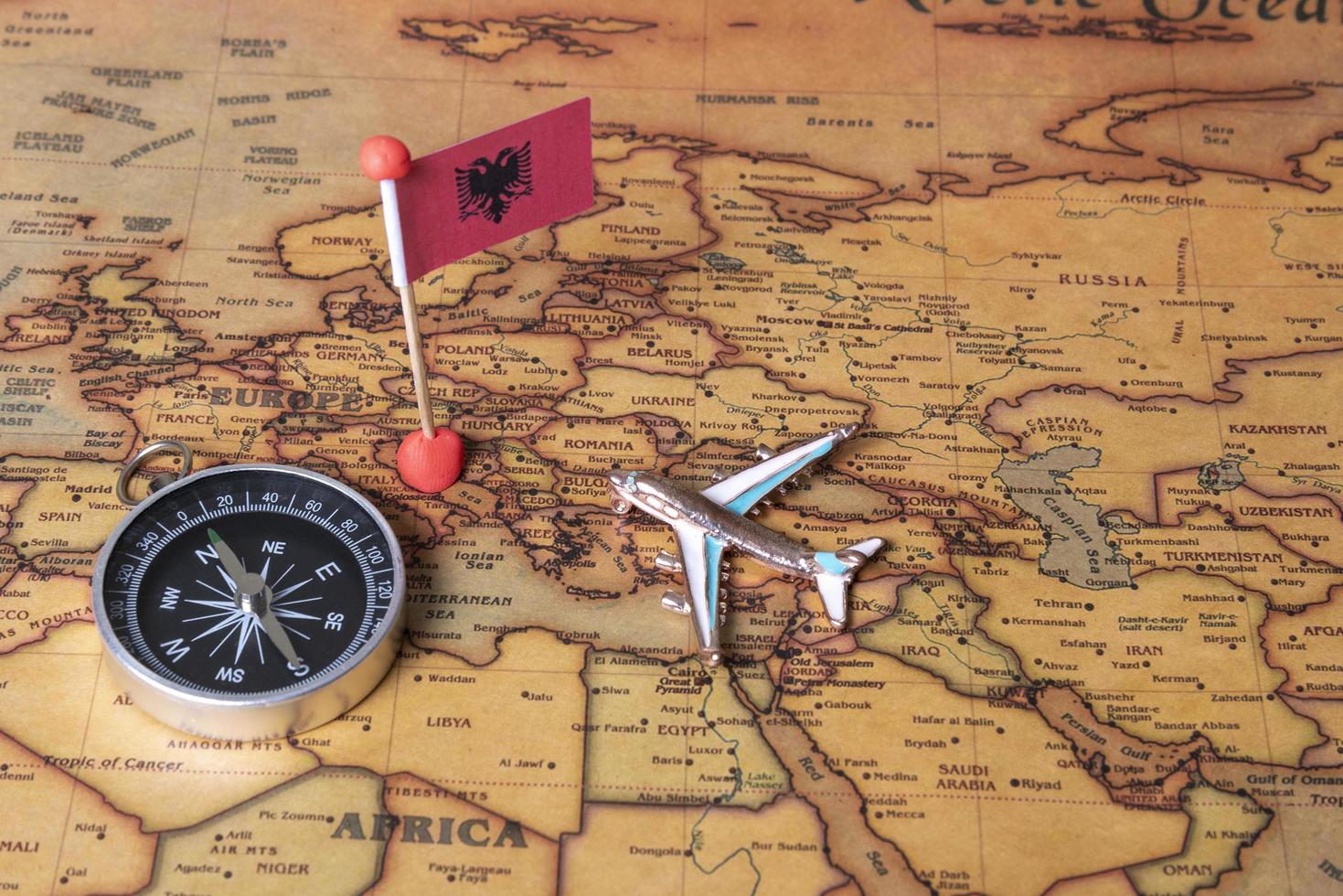 vlag van albanië, kompas en vliegtuig op de wereldkaart. foto