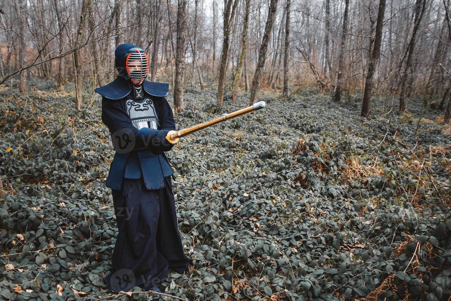 man die kendo beoefent met shinai bamboezwaard op bosachtergrond foto