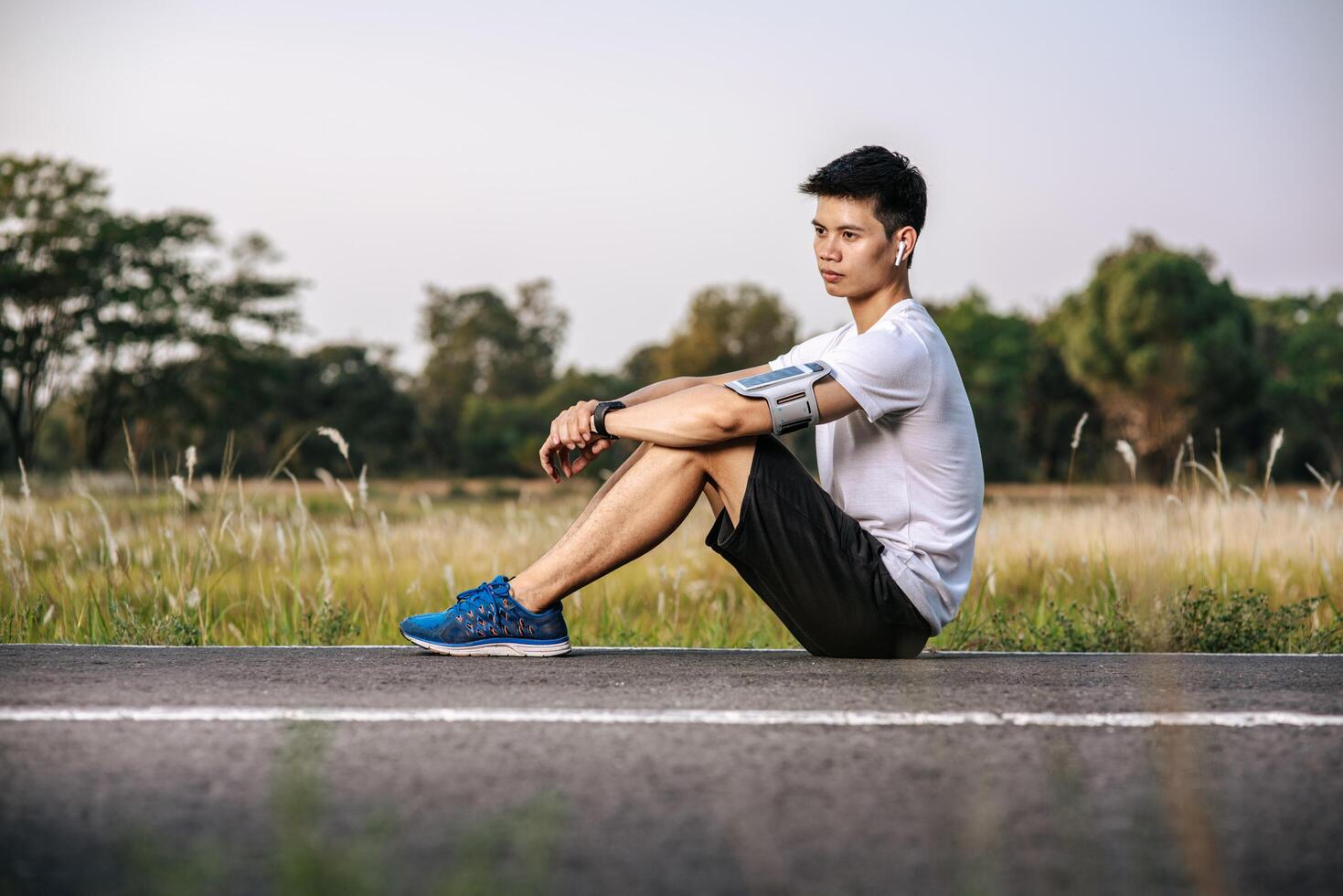 mannen zitten en rusten na het sporten langs de weg. foto