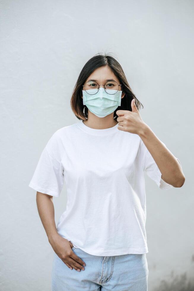 de vrouwen dragen maskers en markeren ze met hun duimen omhoog. foto