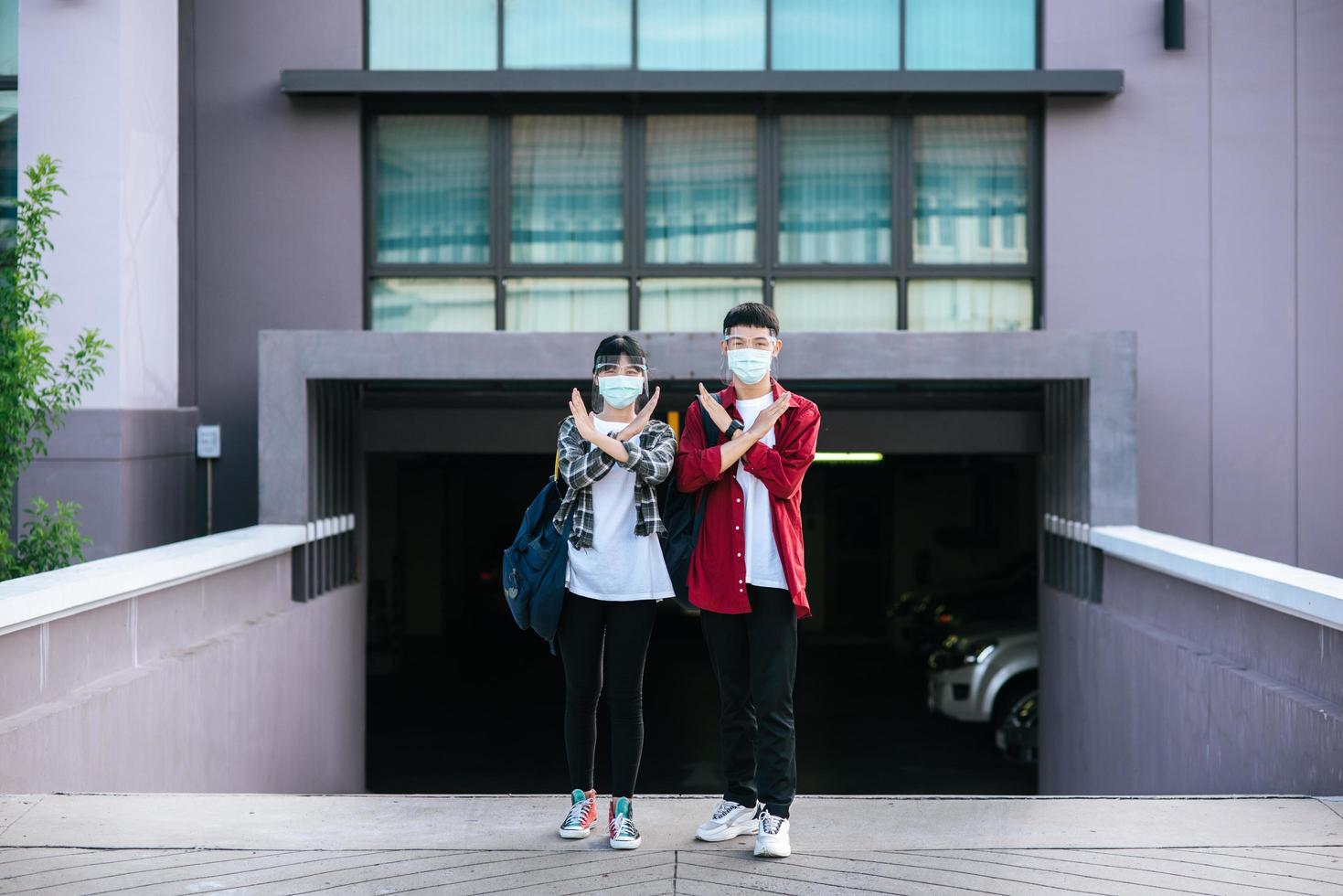 mannelijke en vrouwelijke studenten dragen maskers en staan voor de universiteit. foto