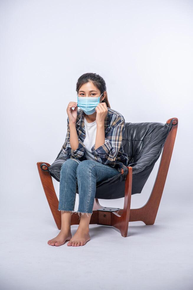 een ongemakkelijke vrouw die op een stoel zit en een masker draagt foto