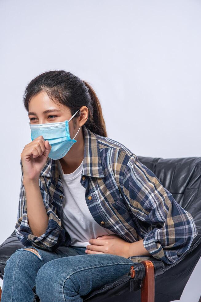 een ongemakkelijke vrouw die op een stoel zit en een masker draagt foto