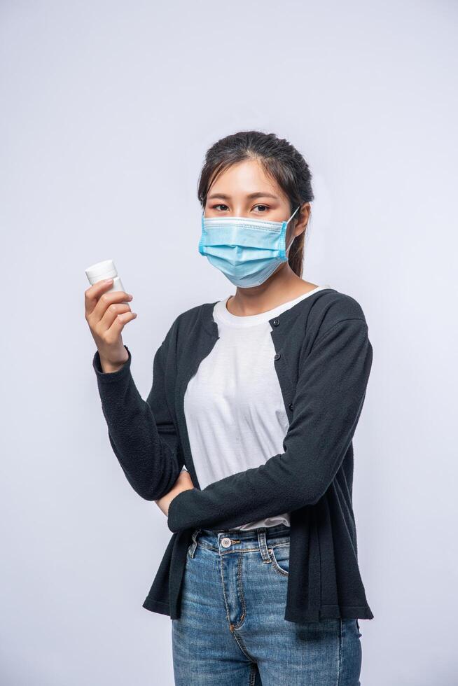 een vrouw die ziek staat met een fles medicijnen foto