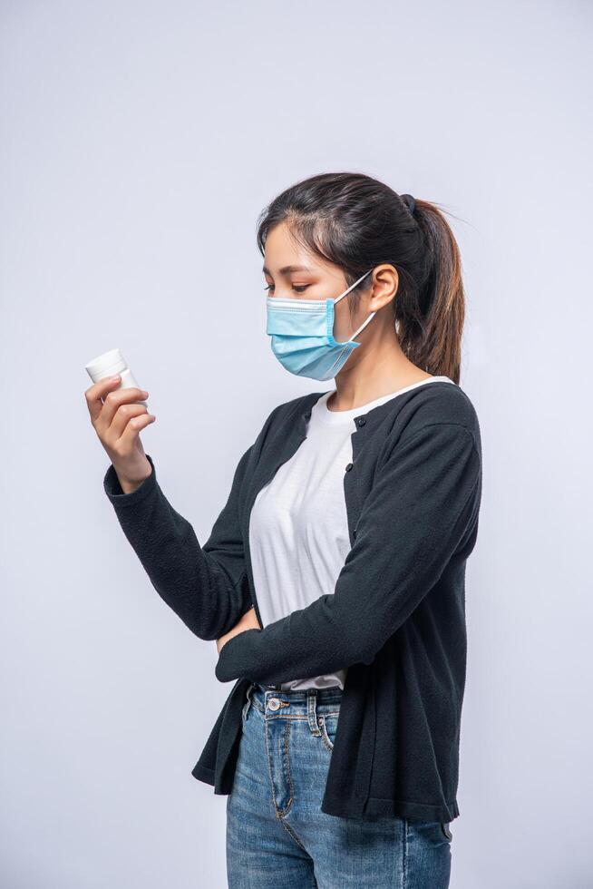 een vrouw die ziek staat met een fles medicijnen foto