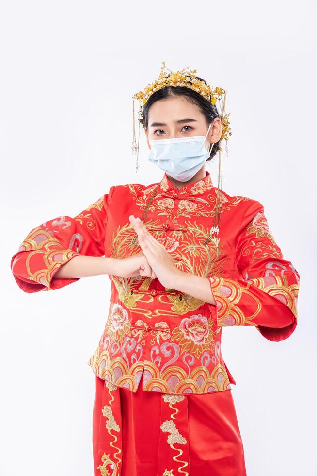 vrouw draagt cheongsam pak en masker welkom klant om te winkelen in chinees nieuwjaar foto
