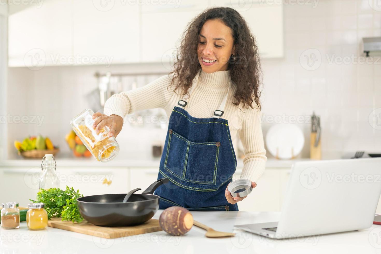 Latijnse vrouw die video opneemt en kookt in de keuken foto