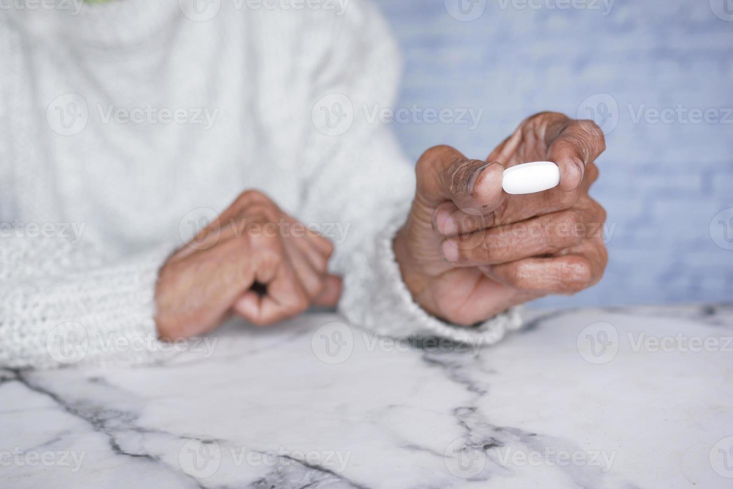 oudere vrouwen die een medische pil vasthouden terwijl ze op hun plaats zitten foto