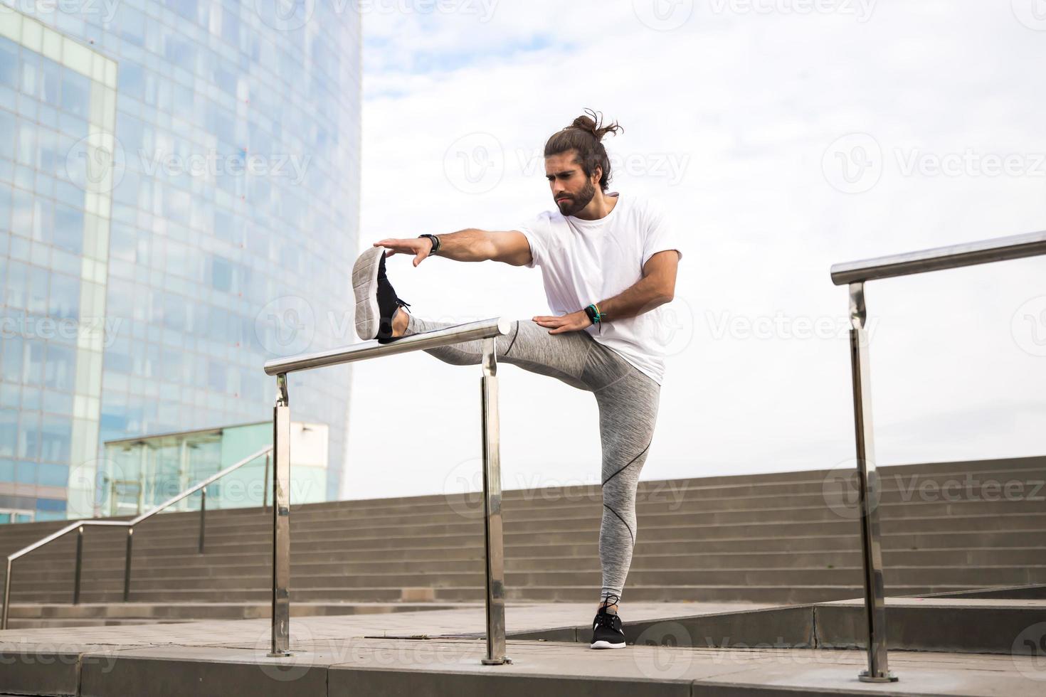 jonge man met lang haar in sportkleding die buiten loopt foto