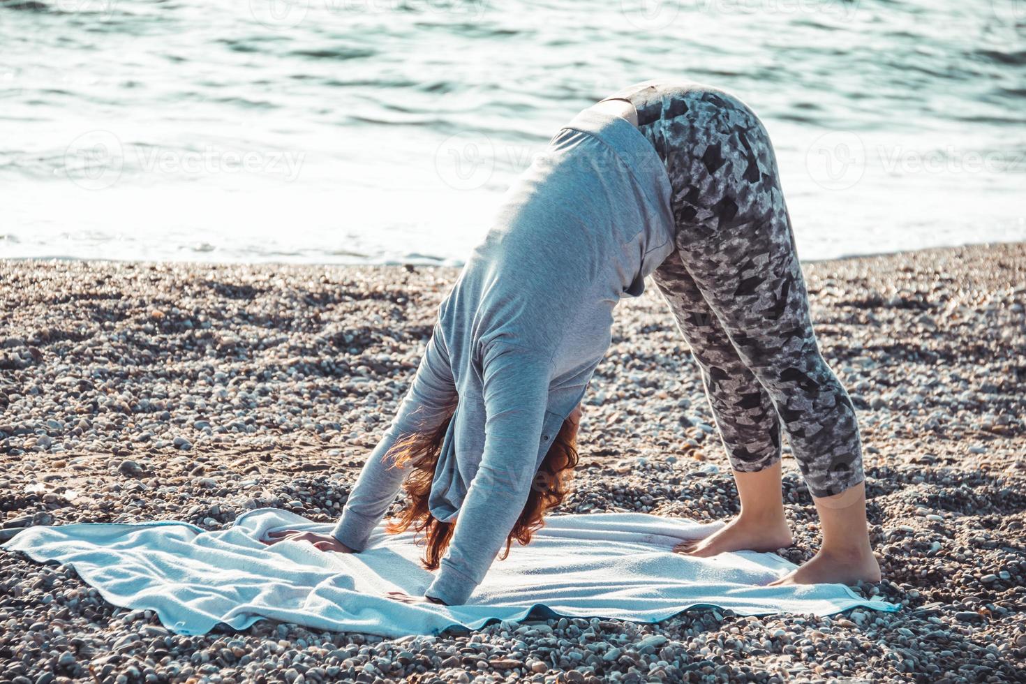 meisje doet yoga en strekt zich uit op het strand foto