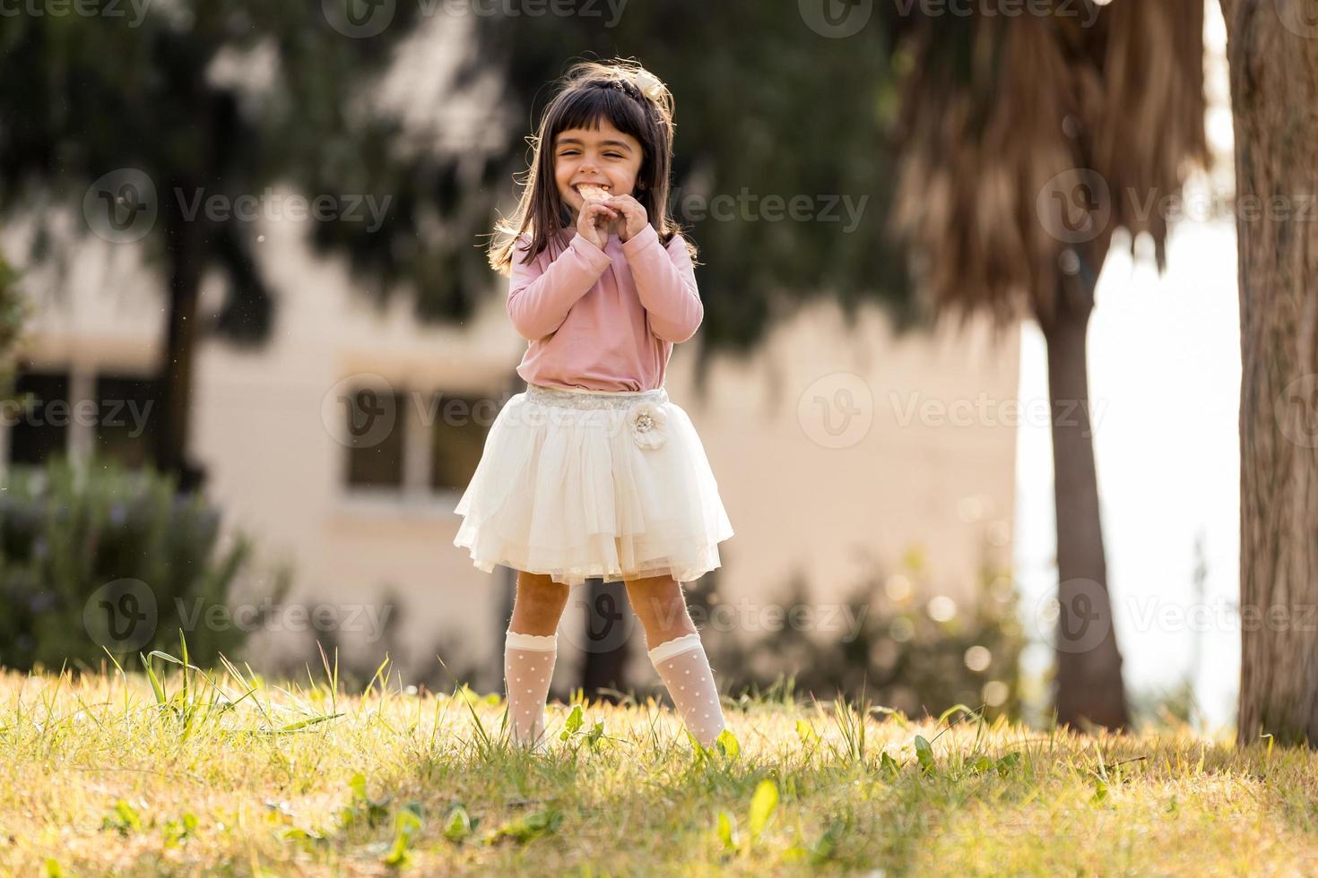 klein meisje dat snoep eet in een park foto