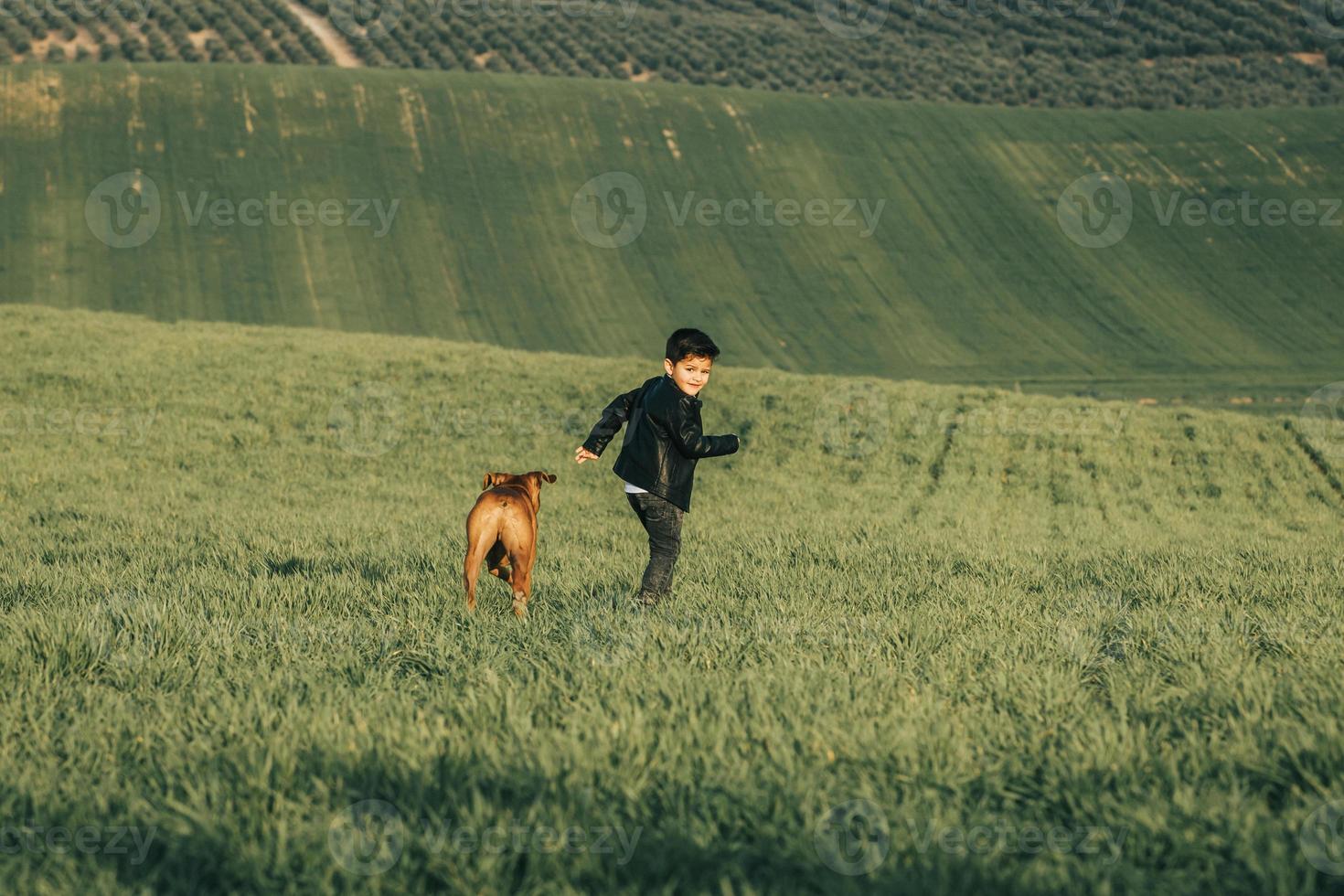modieuze kind in leren jas. stijlvolle kleine jongen met een hond op het platteland foto