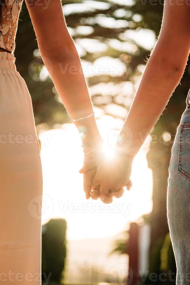 jong lesbisch koppel hand in hand wandelen bij zonsondergang foto