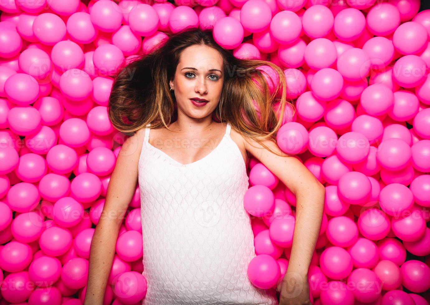 jonge zwangere vrouw die in een roze ballenbad speelt foto