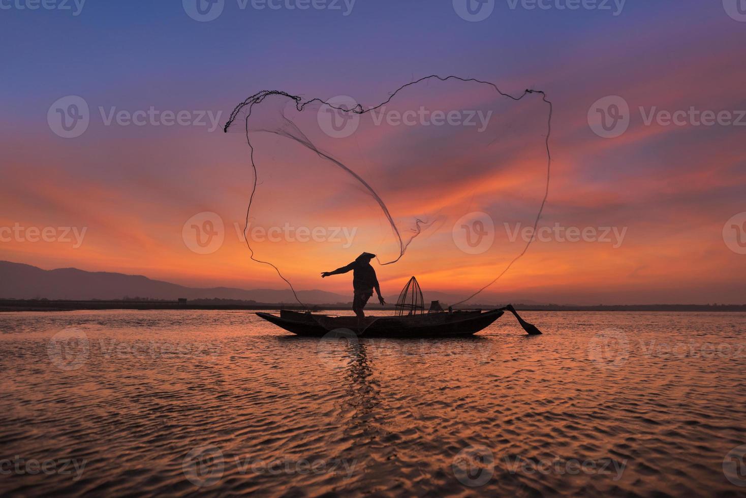 Aziatische visser met zijn houten boot in de natuurrivier in de vroege ochtend voor zonsopgang foto