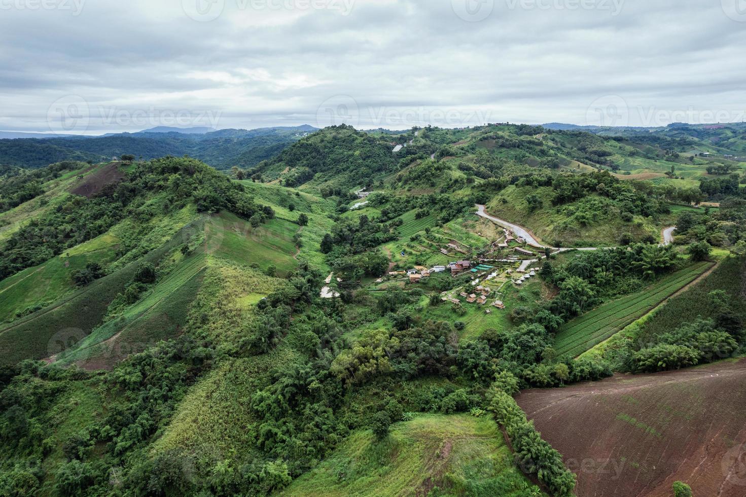 luchtfoto van hutresort op een heuvel tussen de berg in tropisch regenwoud op regenachtige dag foto