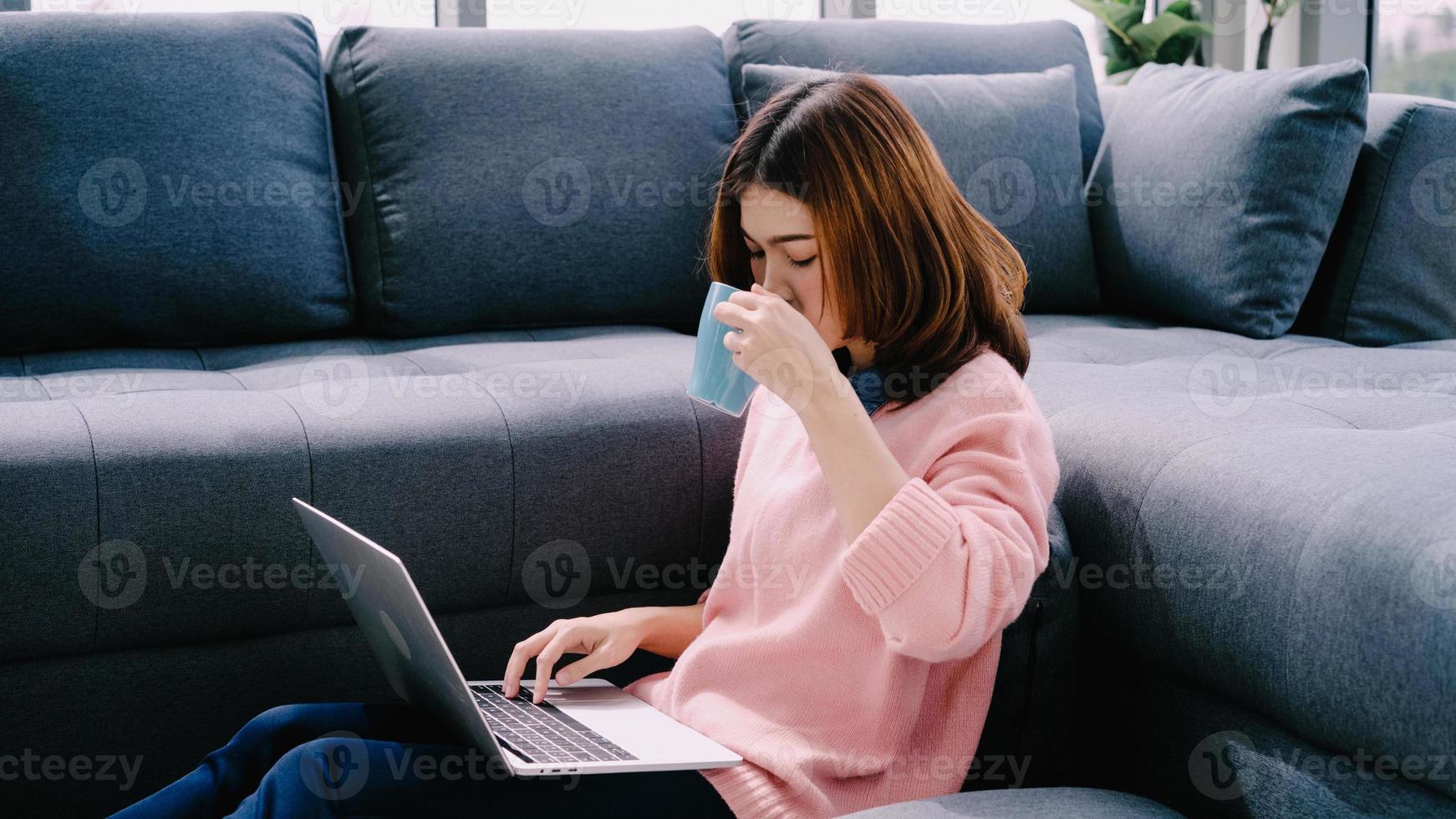 jonge Aziatische vrouw doet onderzoekswerk voor haar bedrijf. lachende vrouw zittend op de bank ontspannen tijdens het browsen op online shopping website. gelukkig meisje dat tijdens vrije tijd thuis door internet bladert. foto