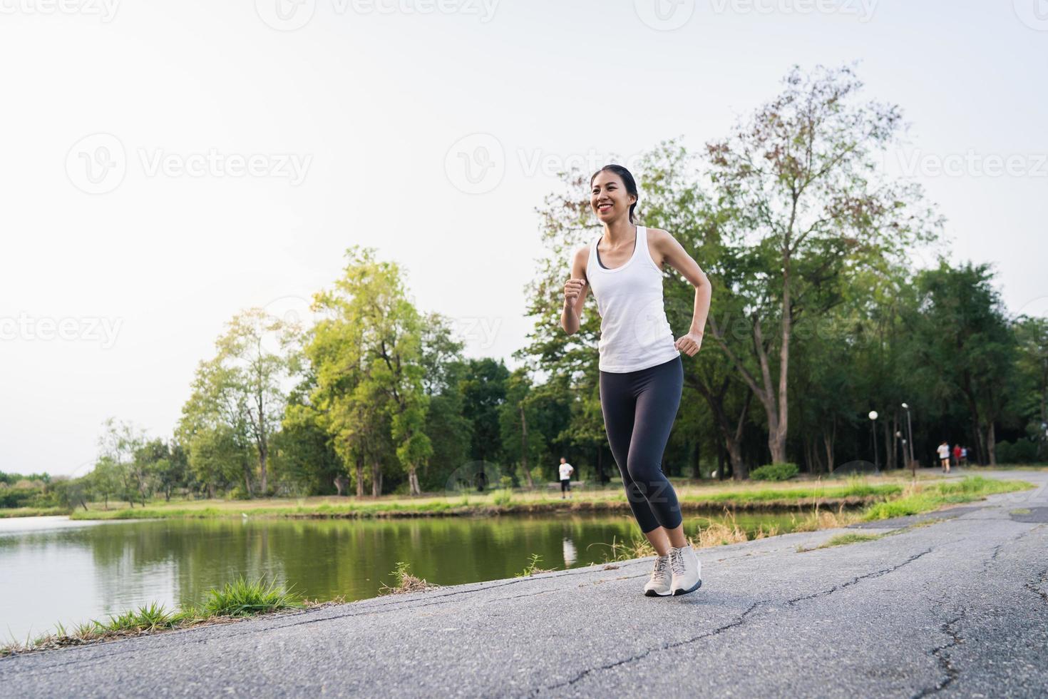 gezonde mooie jonge Aziatische hardloper vrouw in sportkleding rennen en joggen op de stoep in de buurt van het meer in het park in de ochtend. lifestyle fitness en actieve vrouwen oefenen in stedelijk stadsconcept. foto