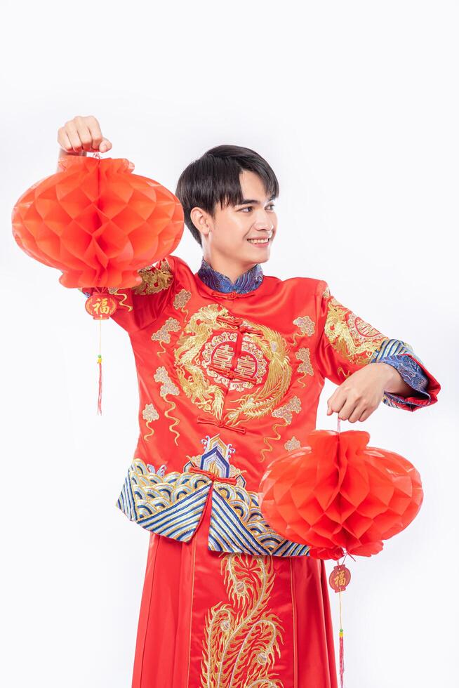 man draagt cheongsam pak show versier rode lamp naar zijn winkel in Chinees nieuwjaar foto