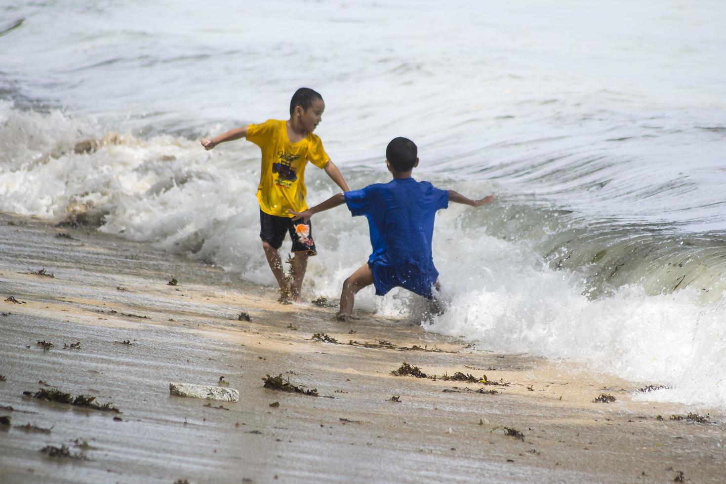 sorong, west papua, indonesië, 12 december 2021. jongens spelen tegen de golven op het strand foto