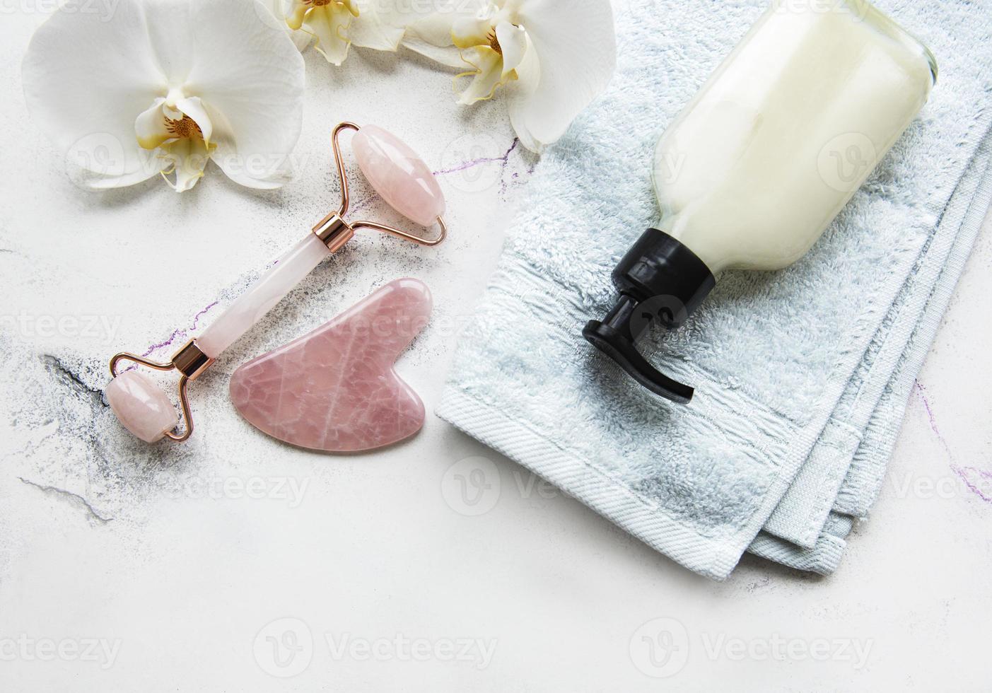 gezichtsmassage jade roller met cosmetisch product op witte marmeren achtergrond foto