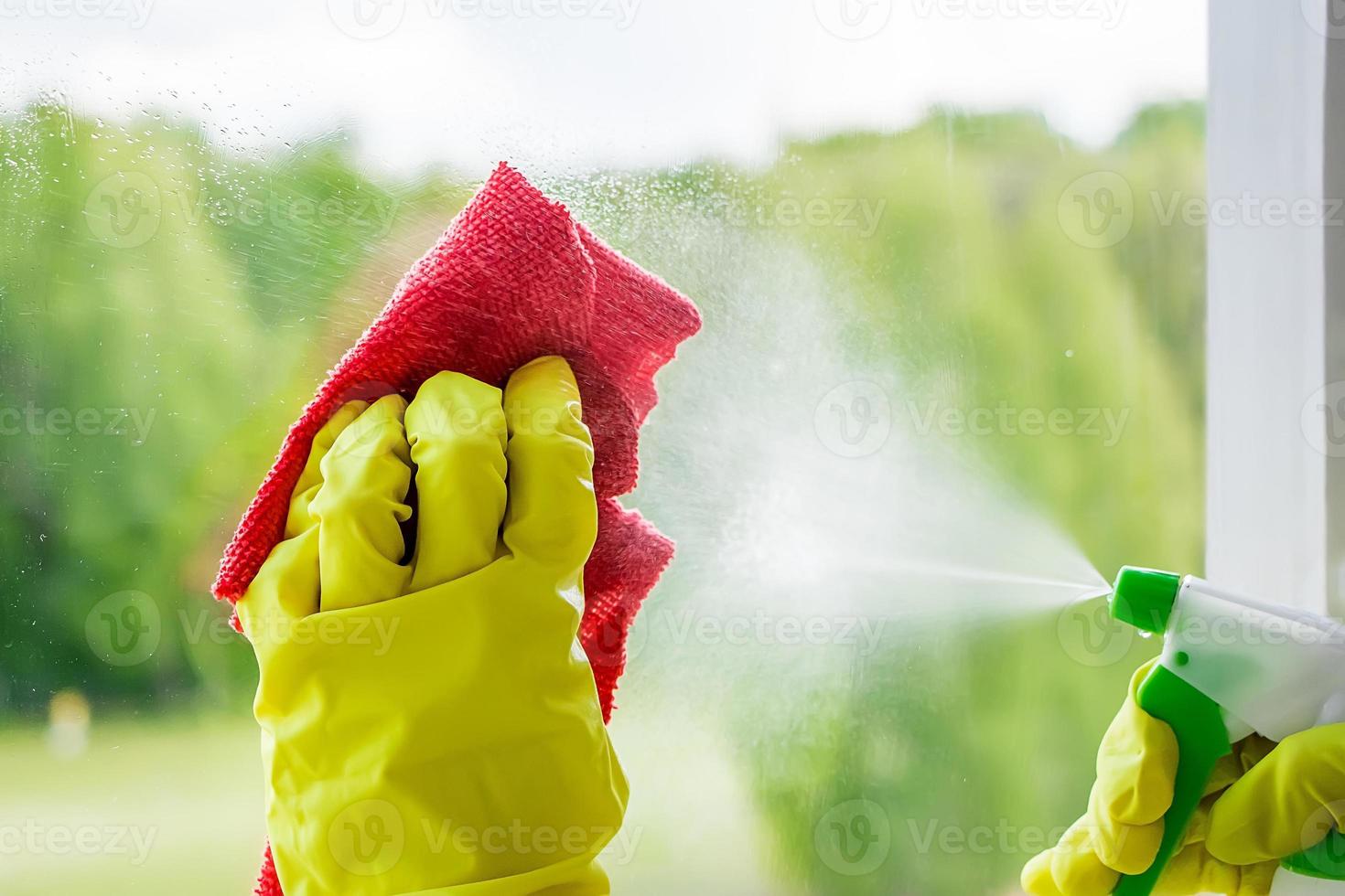 vrouw in gele rubberen handschoenen veegt het glas af. foto