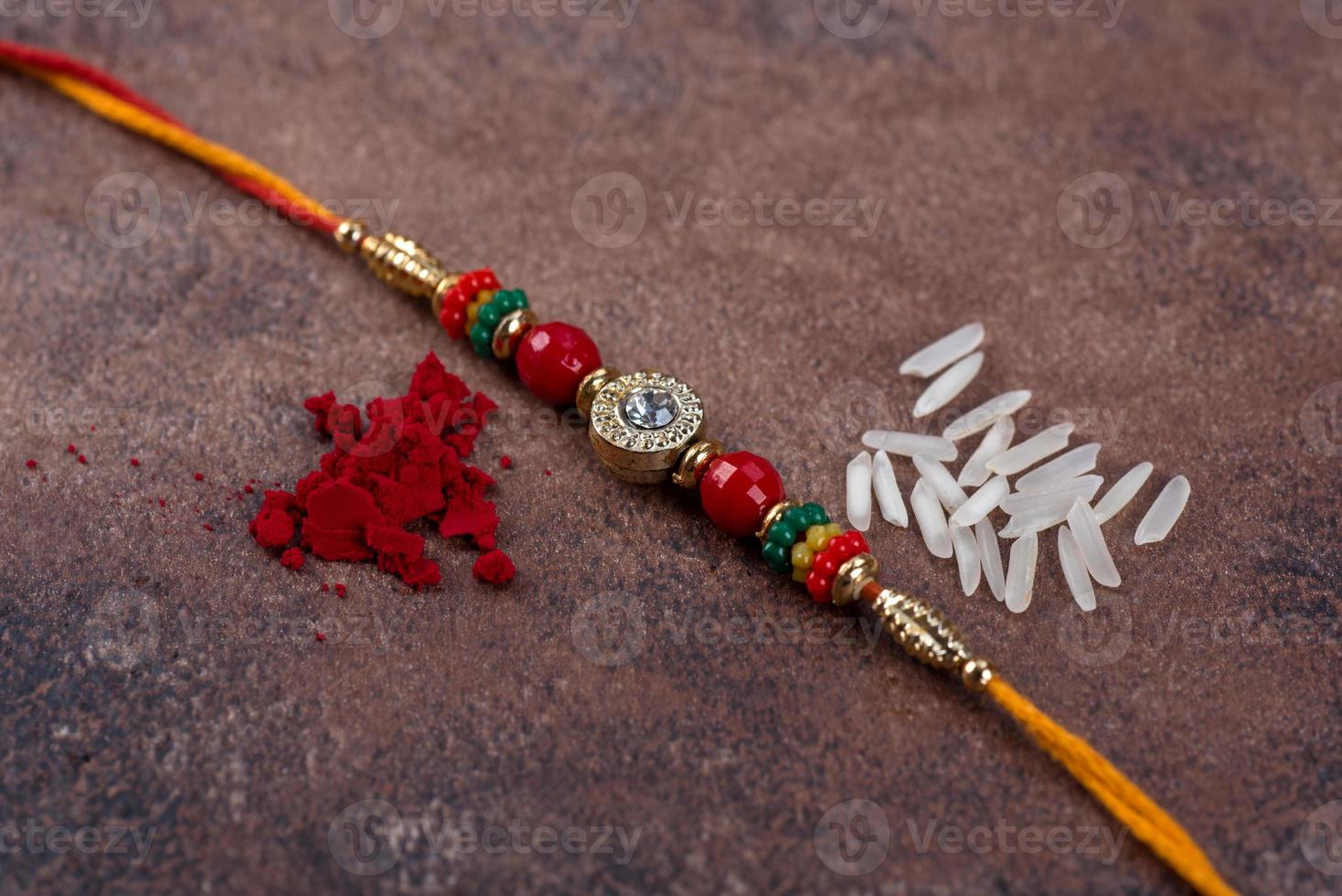 raksha bandhan rakhi met rijstkorrels en kumkum op stenen achtergrond, traditionele Indiase polsband die een symbool is van liefde tussen broers en zussen. foto