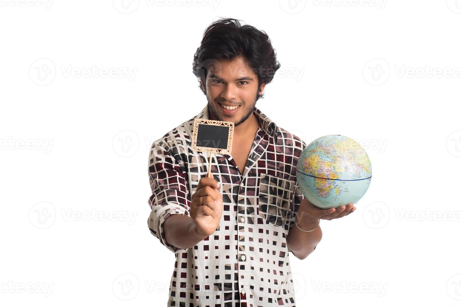 jonge man met een wereldbol en een klein bord op een witte achtergrond. foto