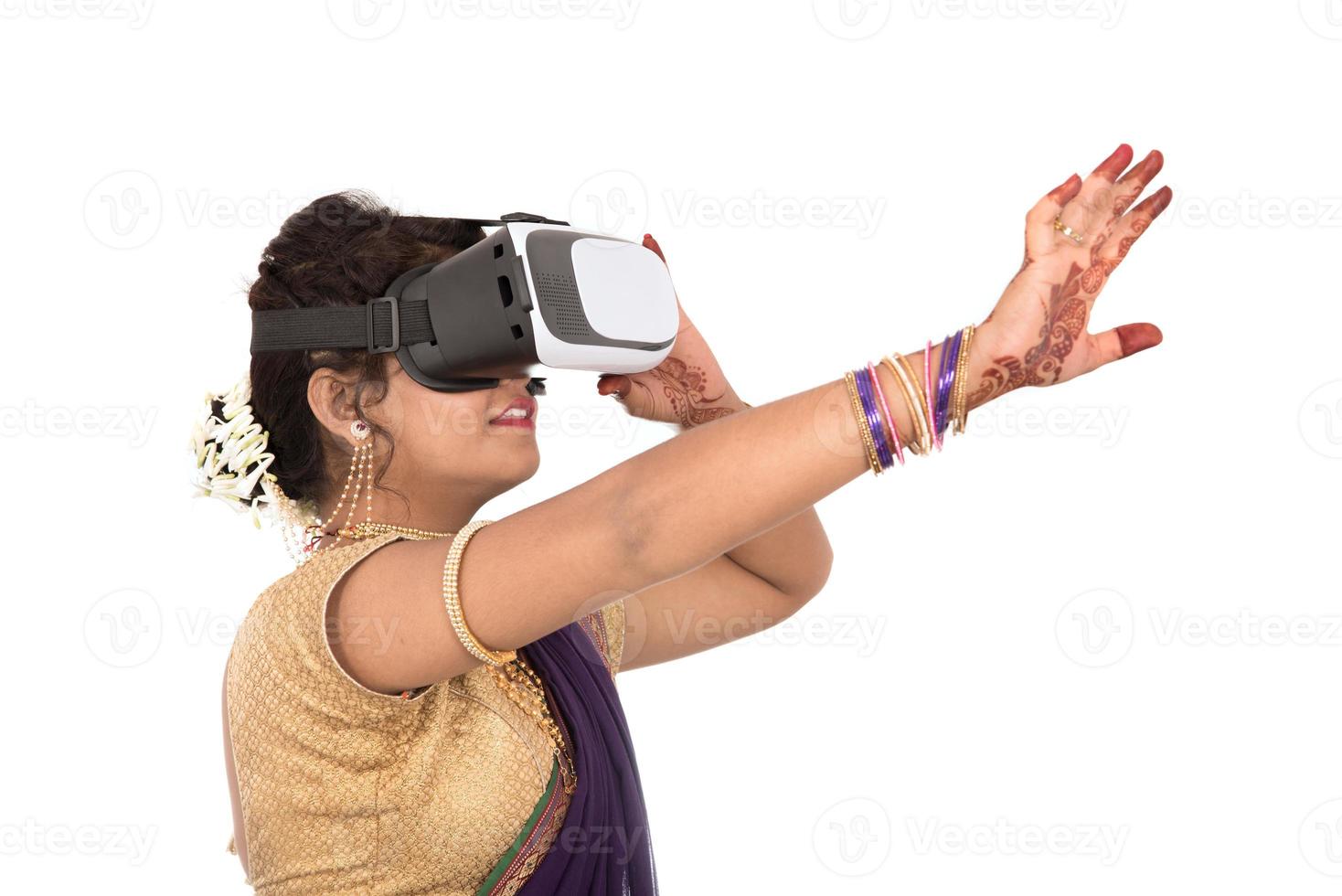 Indiase traditionele jonge vrouw in saree die door een vr-apparaat kijkt foto