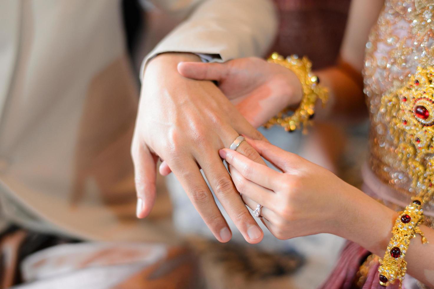 bruid en bruidegom die trouwring op vinger zetten, Thaise huwelijksverlovingsceremonie foto
