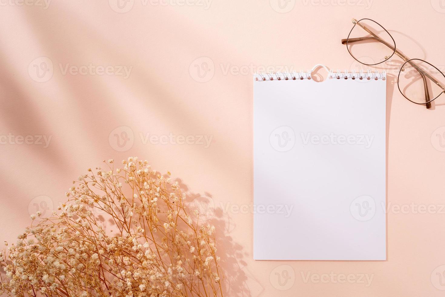 minimalistische lege spiraalkalender voor mock-up, trendy bril en bloemen op beige achtergrond foto