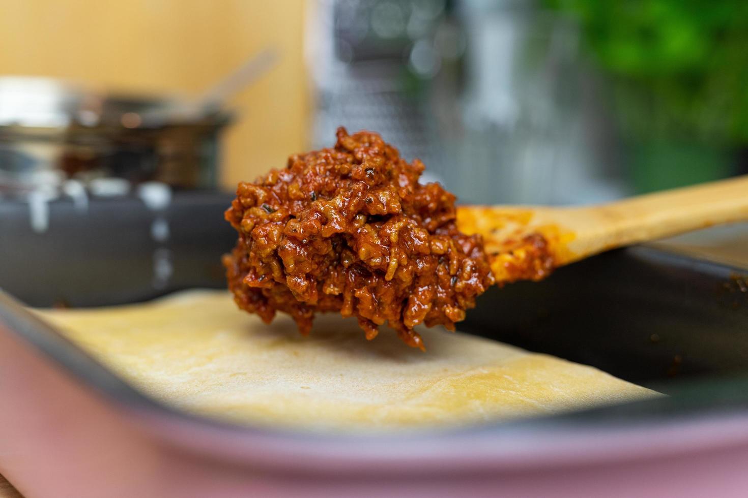 rundvlees met tomatensaus op plakken pasta zetten. bereiding van lasagne. foto