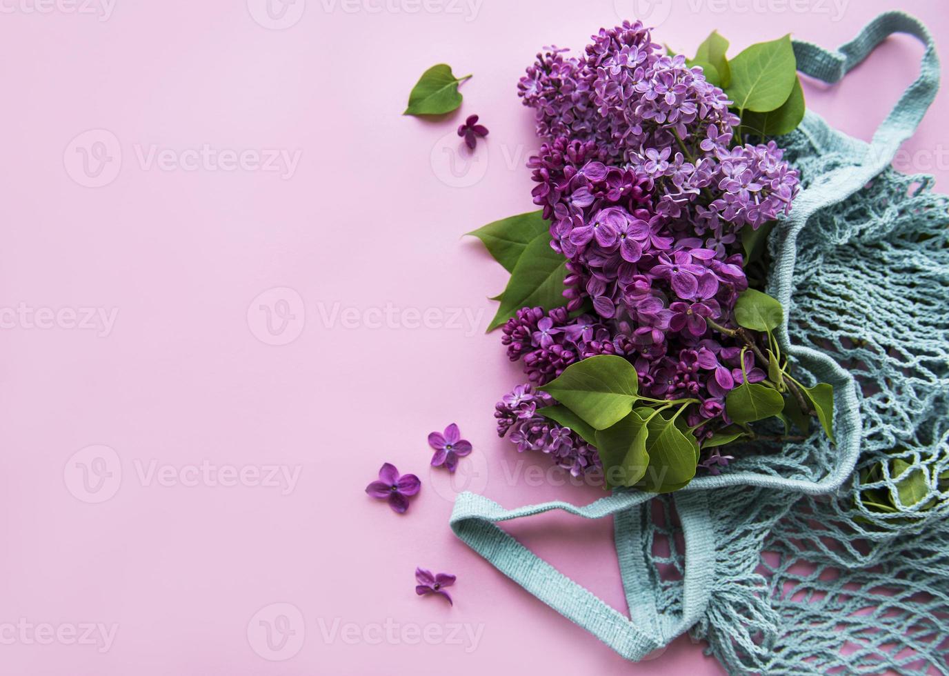 boeket van lila in herbruikbare eco mesh tas op roze achtergrond. concept geen plastic, geen afval. kopieer ruimte bovenaanzicht sjabloon voor wenskaart, briefkaart, uitnodiging. foto