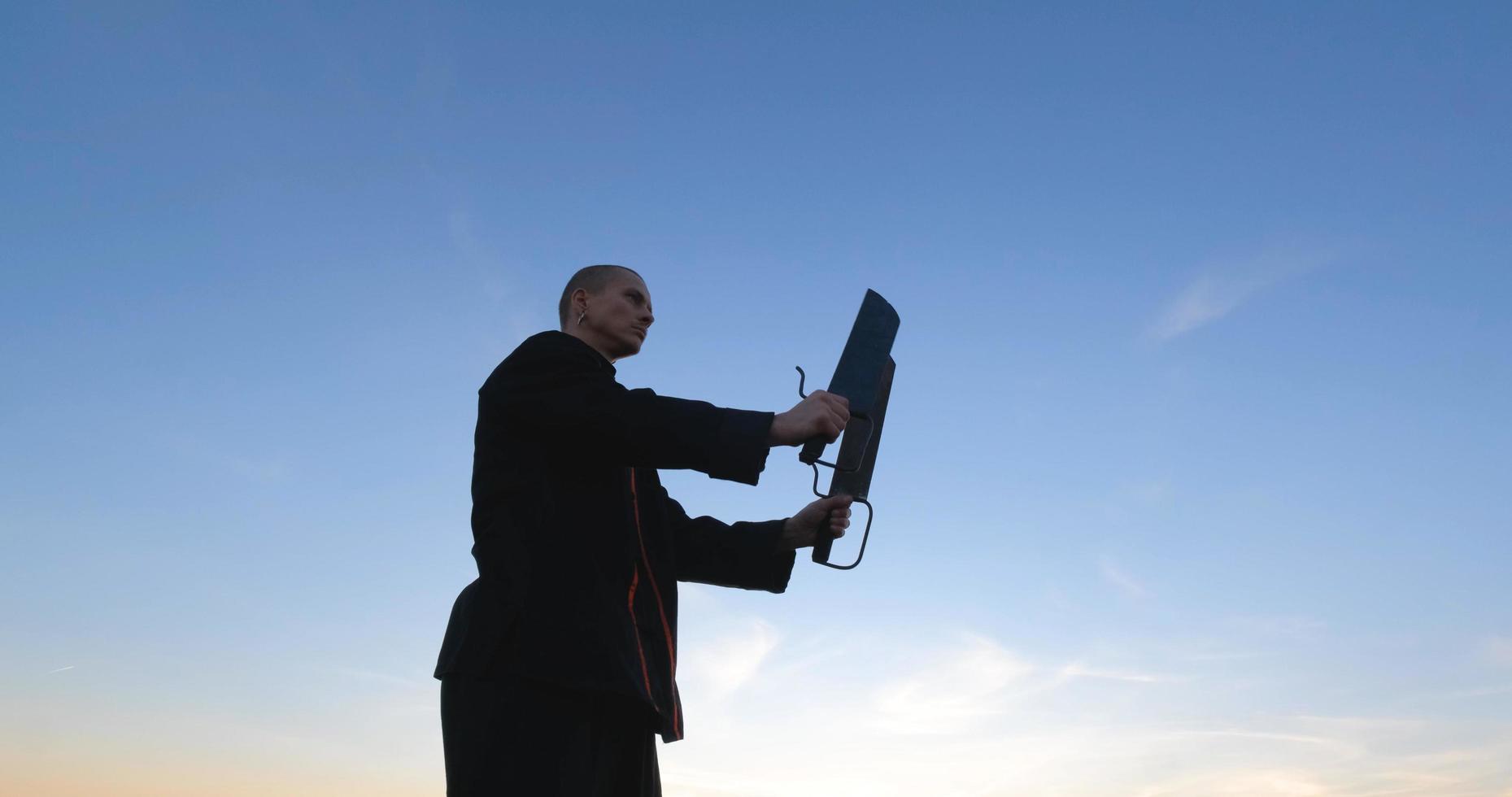 silhouet van jonge mannelijke kungfu-jager die alleen in de velden oefent tijdens zonsondergang foto