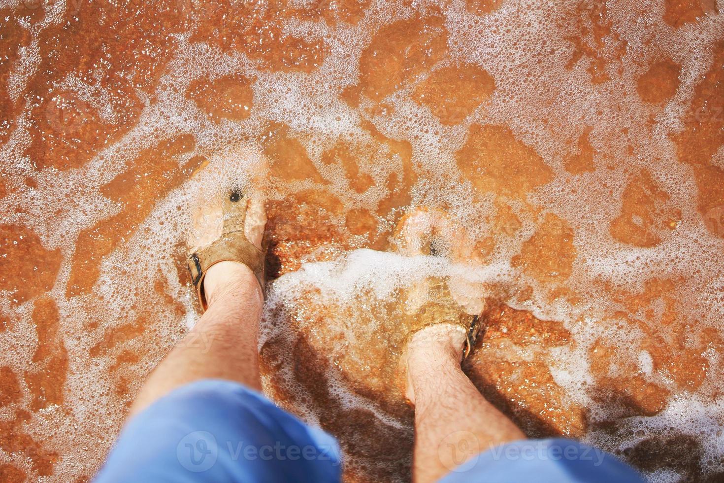 mannen voeten in sandalen op het strand. foto