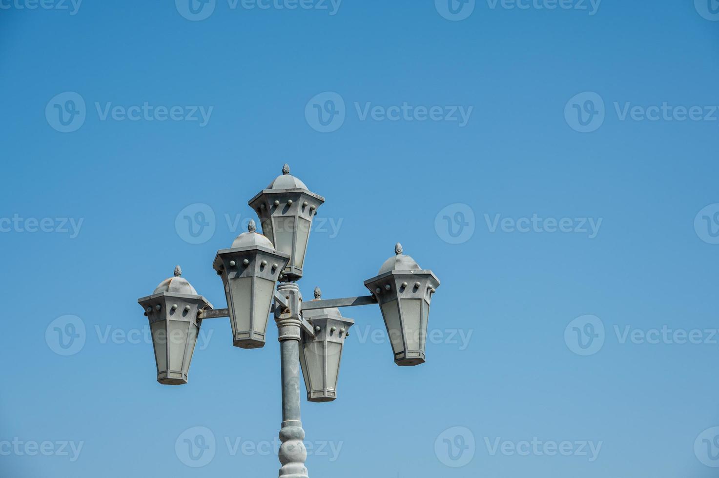 vijf veelhoekige straatlantaarns onder een pilaar in de blauwe lucht foto