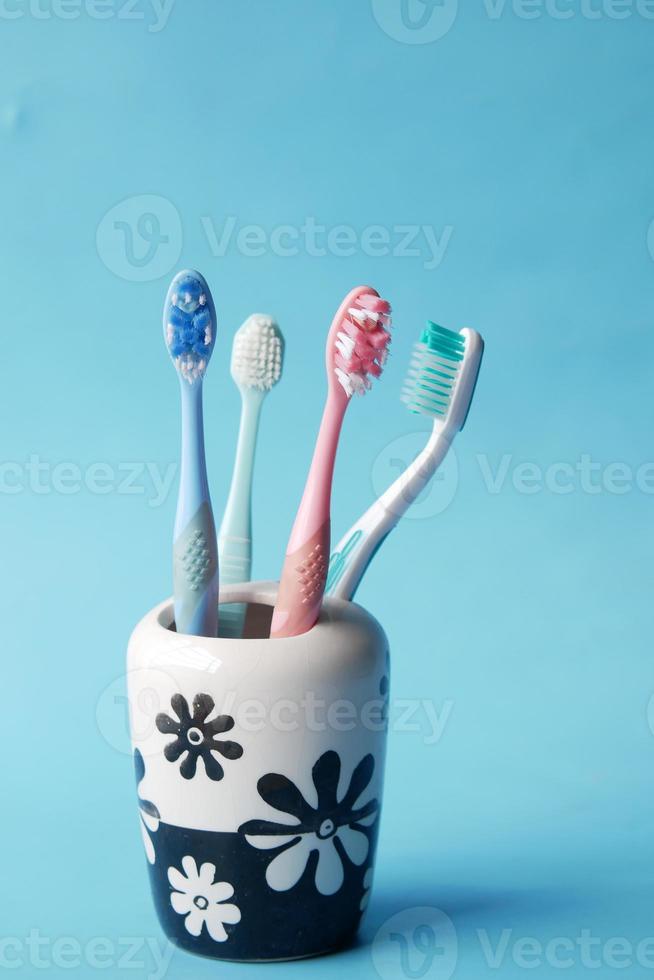 kleurrijke tandenborstels in witte mok tegen blauwe achtergrond foto