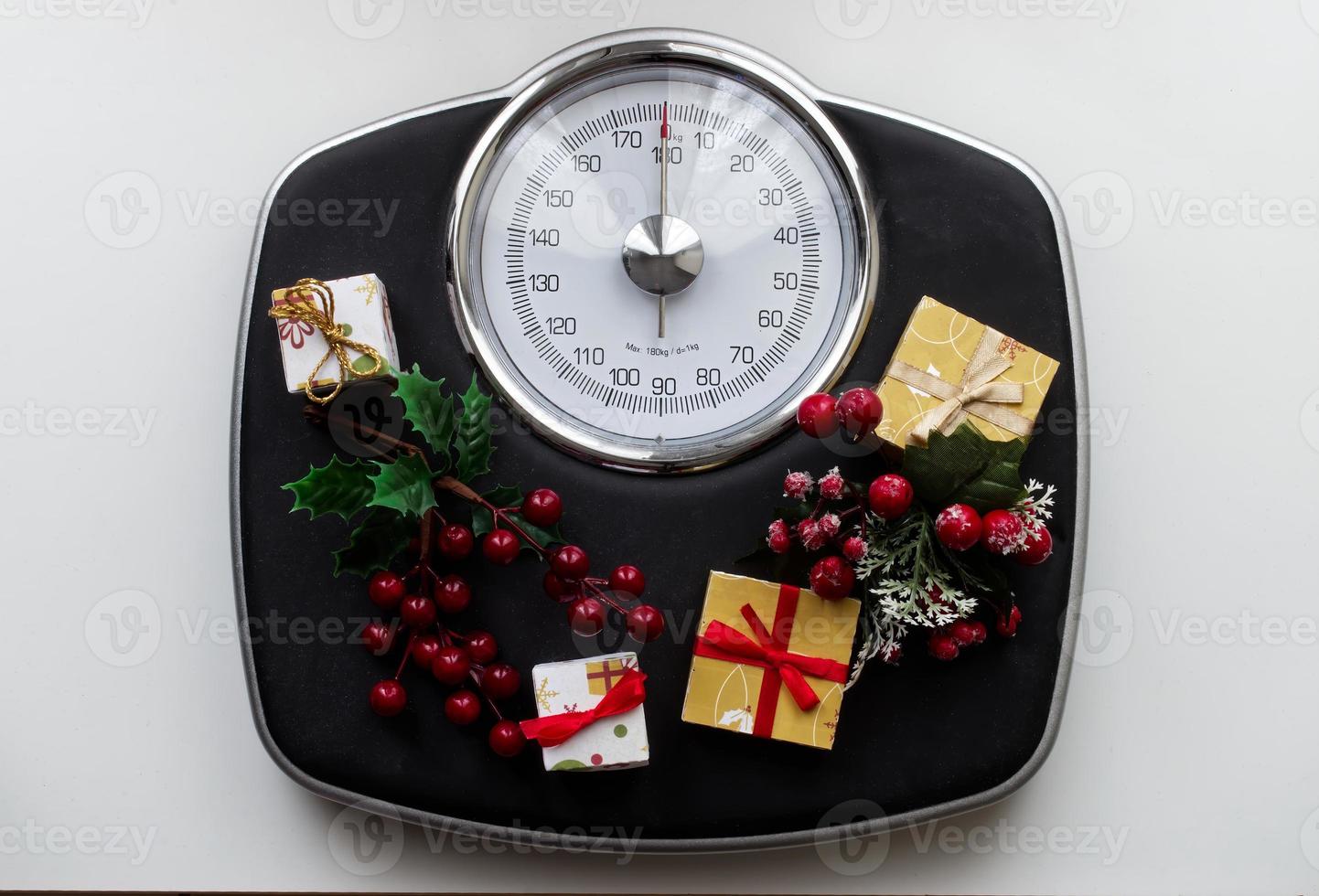 analoge schaal omringd door kerstversieringen en geschenken. overgewicht na kerstvakantie. begin dieetconcept. foto