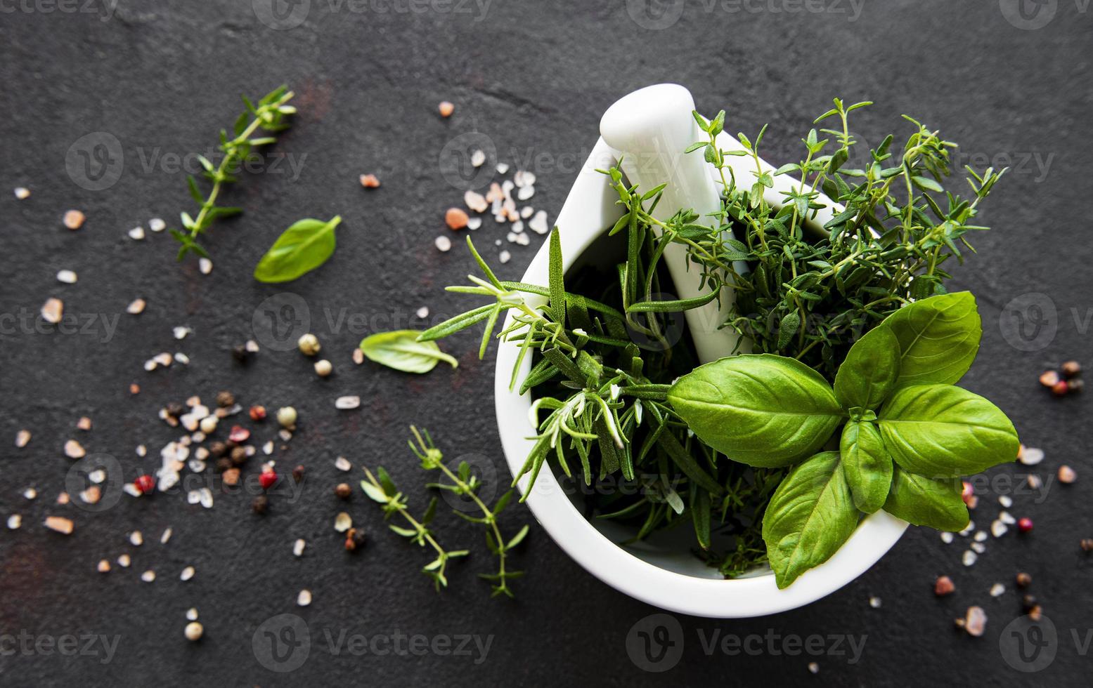 stelletje aromatische kruiden in mortel op een zwarte betonnen ondergrond foto