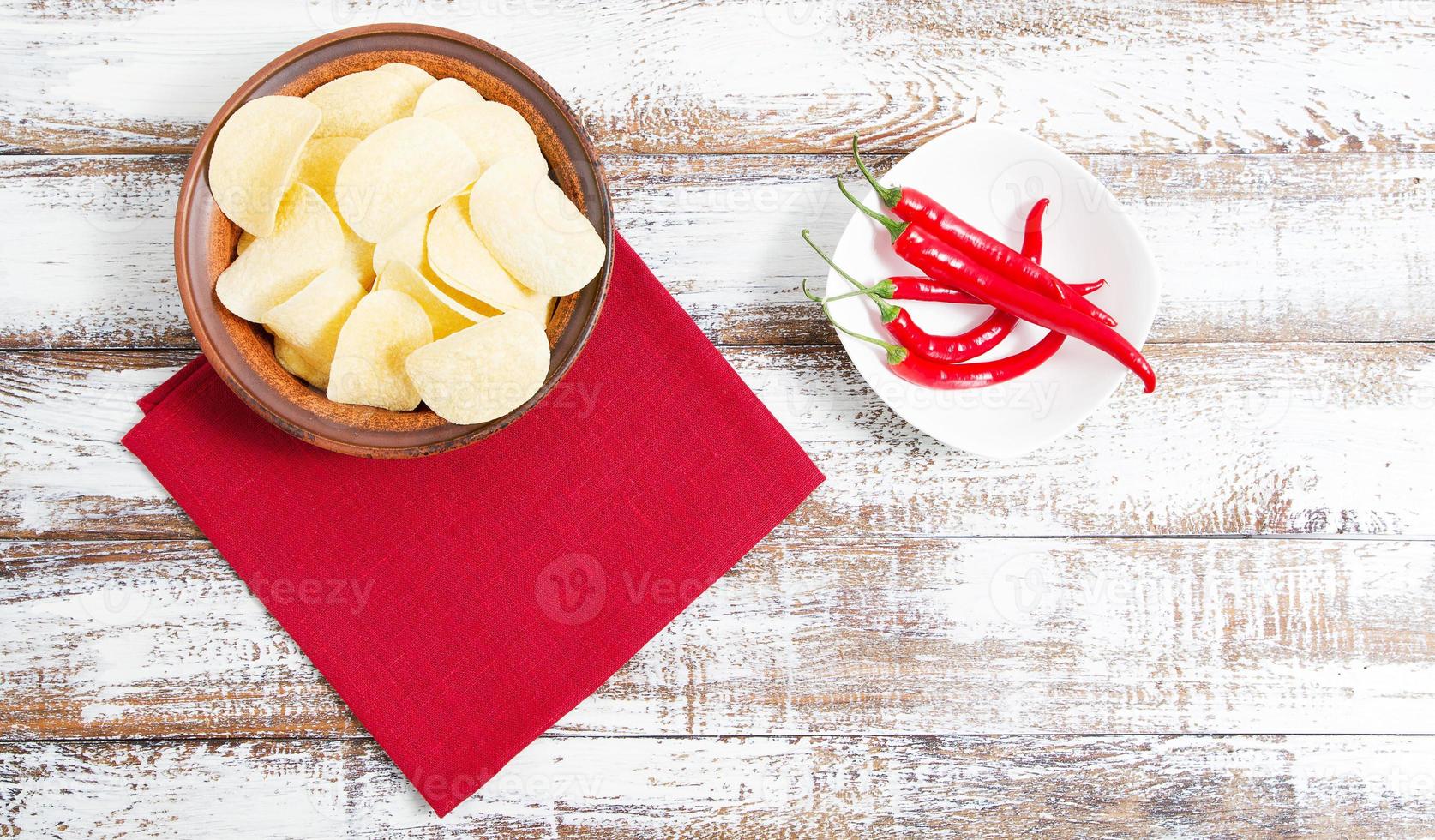 bespotten van chips op plaat, hete peper en rode servet op houten tafel - kopieer ruimte foto