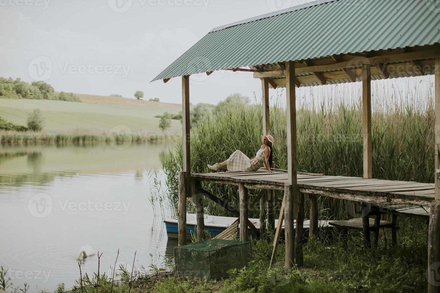 ontspannende jonge vrouw op houten pier aan het meer foto