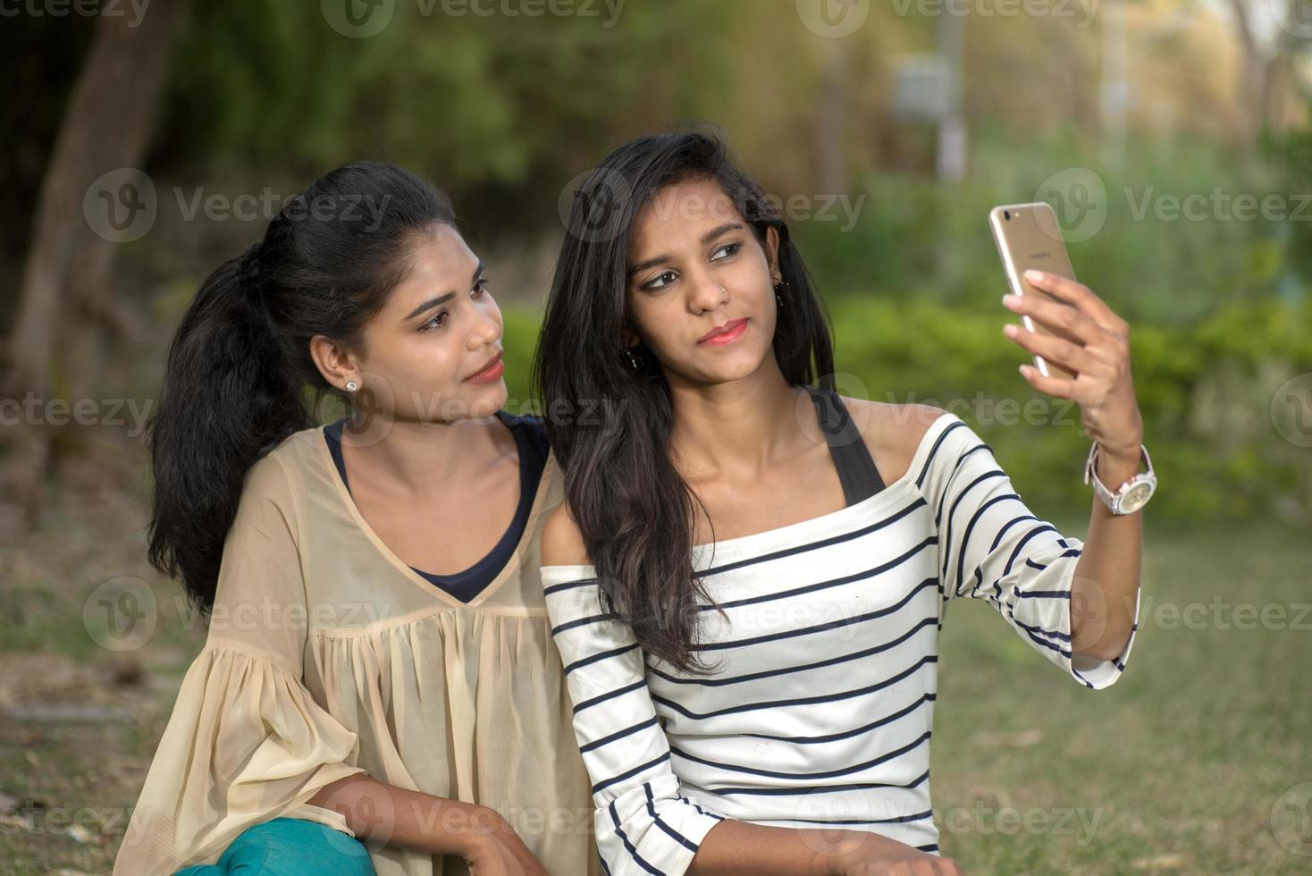 twee mooie vrouwelijke vrienden die selfie met smartphone in openlucht nemen. foto