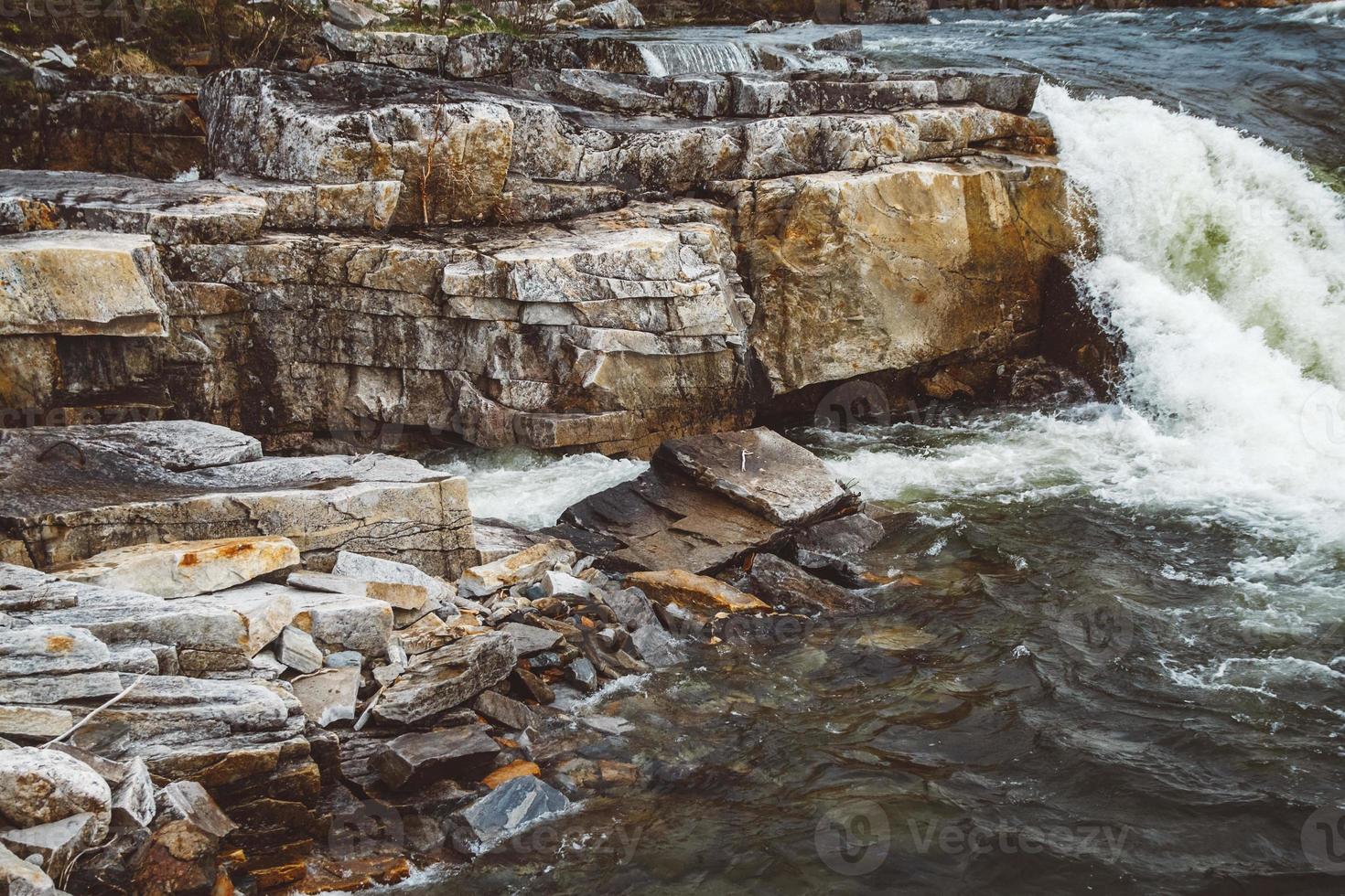 stroom van rivier tussen stenen en rotsen. stroom in stenen bed, snelle bergrivier tussen rotsen, water kookt in stromende stroom foto