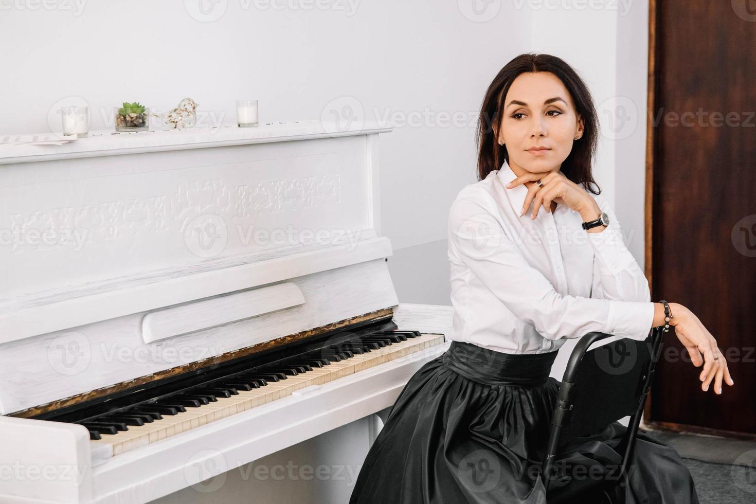 mooie vrouw gekleed in wit overhemd spelen op witte piano. plaats voor tekst of reclame foto