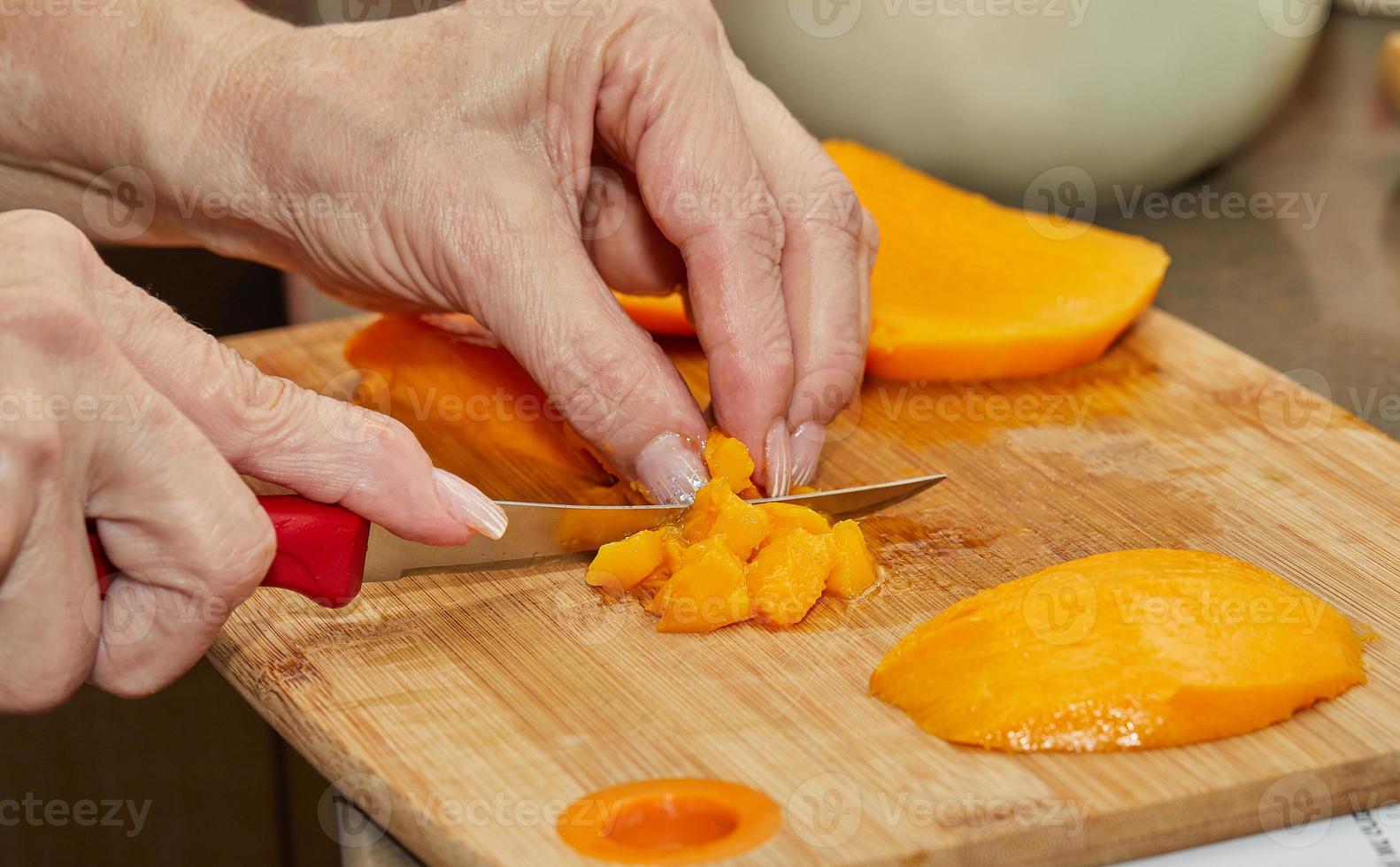 Cook snijdt sappige mango in plakjes voor het maken van salade foto