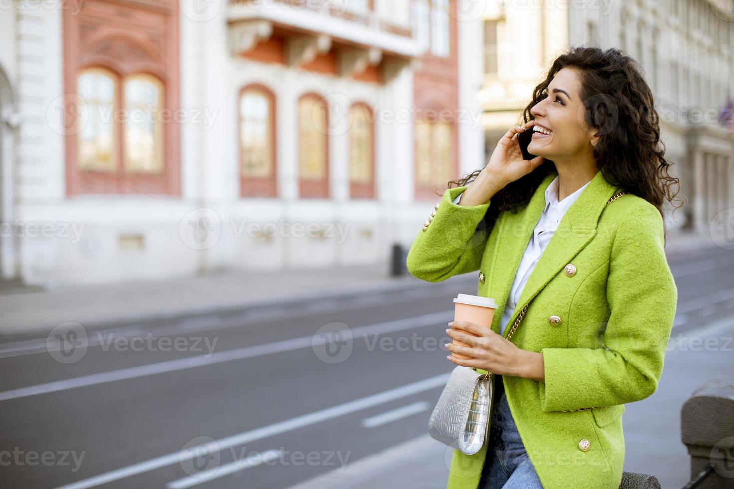 jonge vrouw die smartphone op straat gebruikt en afhaalkoffie houdt foto