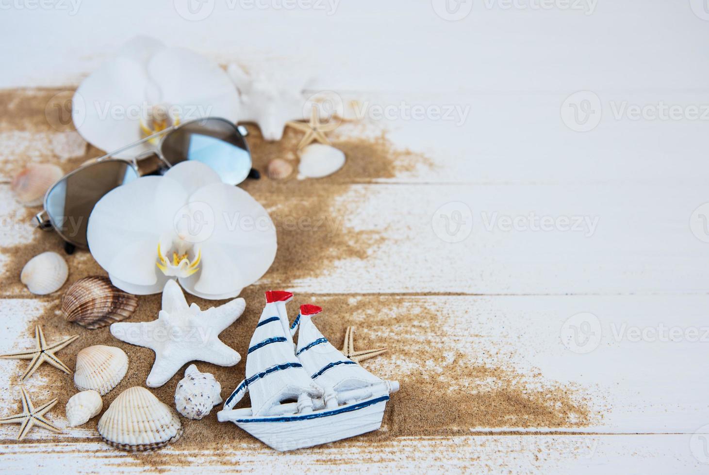 schelpen met zand, orchideeën en zonnebril foto