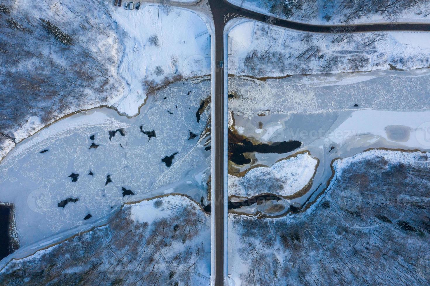 winterseizoen luchtfoto van boven naar beneden uitzicht op een brug met een rechte lijnweg over de rivier foto